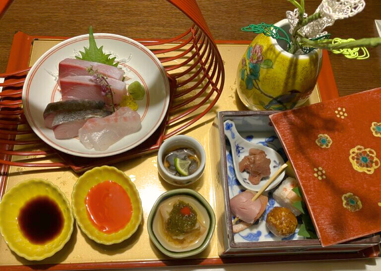 界 加賀の夕食“宝楽盛り”。加賀水引の飾りが添えられた器や九谷焼の花瓶が華やかさを添える、八寸・お造り・酢の物の盛り合わせ