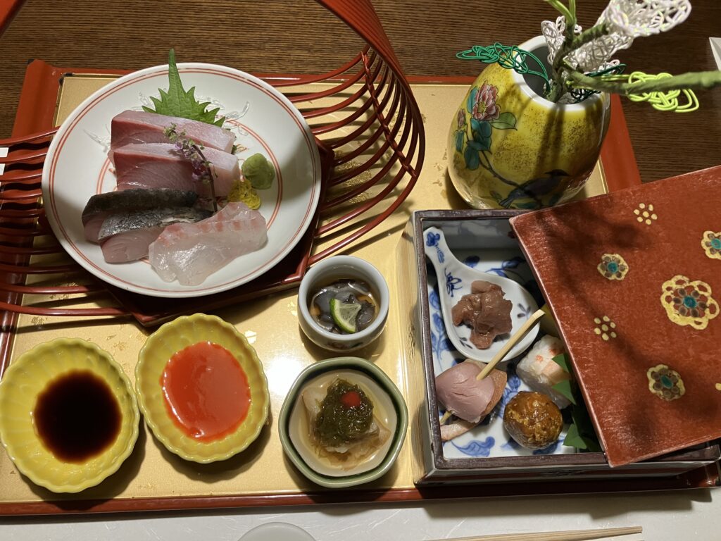 界 加賀の夕食“宝楽盛り”。加賀水引の飾りが添えられた器や九谷焼の花瓶が華やかさを添える、八寸・お造り・酢の物の盛り合わせ